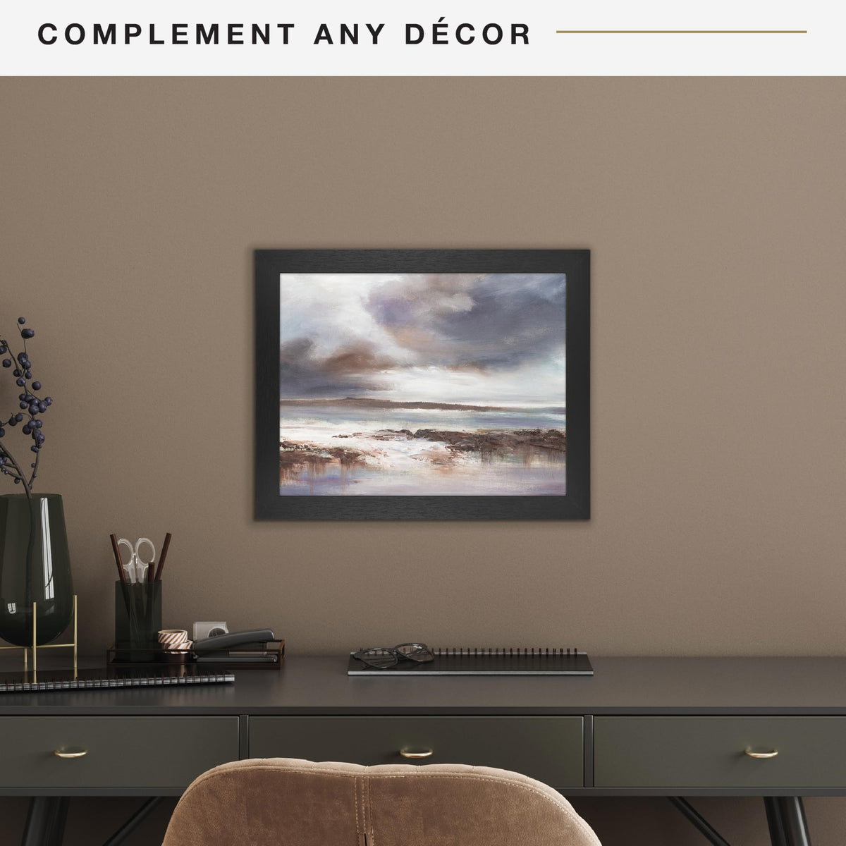 Framed artwork on a wall above a desk with office supplies.